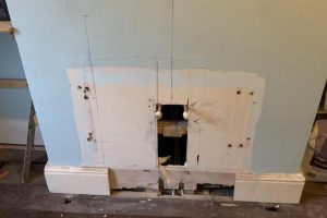 Radiator removed, pipes capped and old fireplace exposed
